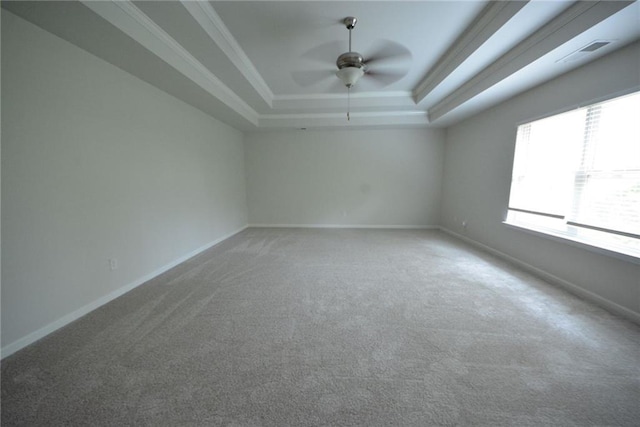 carpeted spare room with a tray ceiling, ceiling fan, baseboards, and ornamental molding