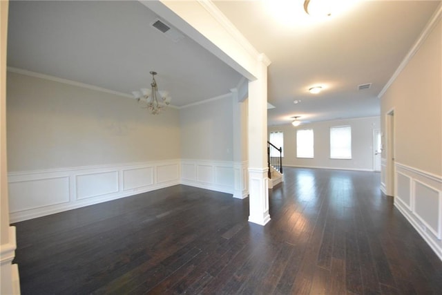 unfurnished dining area with a chandelier, crown molding, dark wood-style flooring, a wainscoted wall, and a decorative wall