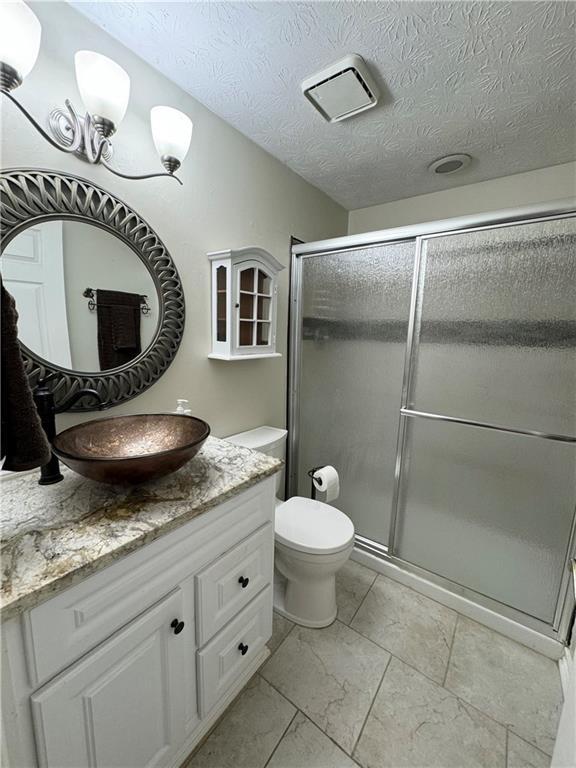 2606 Ramblewood Ct, Acworth, GA 30102 - bathroom with walk in shower, vanity, a textured ceiling, and toilet