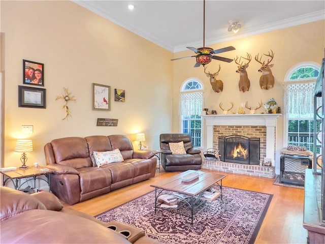 living room with a fireplace, wood-type flooring, crown molding, and a healthy amount of sunlight