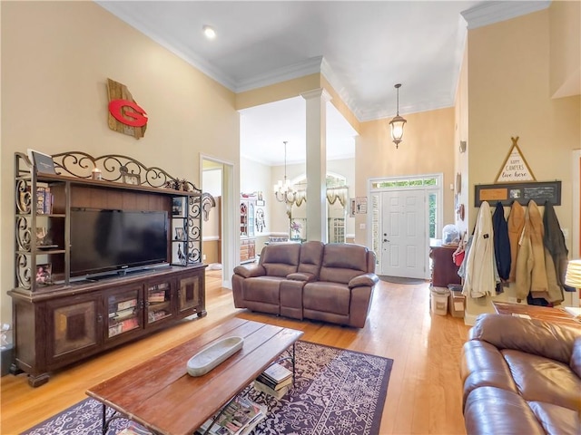 living room with plenty of natural light, light wood-type flooring, crown molding, and a chandelier