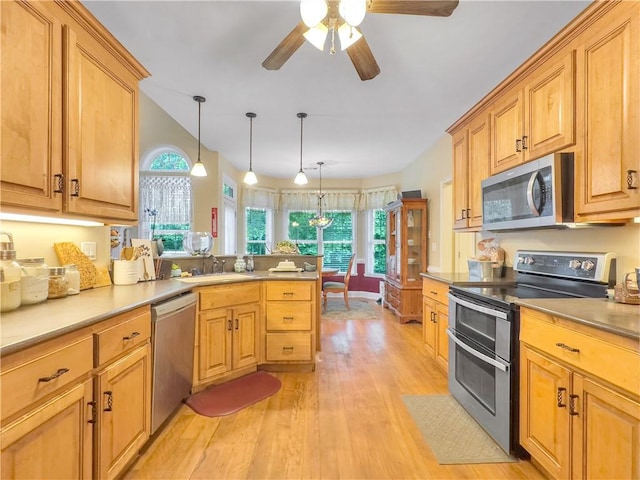 kitchen with kitchen peninsula, stainless steel appliances, sink, light hardwood / wood-style floors, and hanging light fixtures