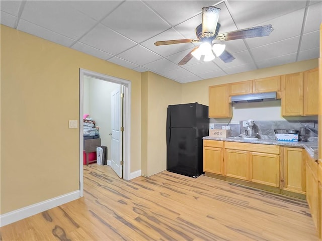 kitchen with a paneled ceiling, ceiling fan, black refrigerator, and light wood-type flooring