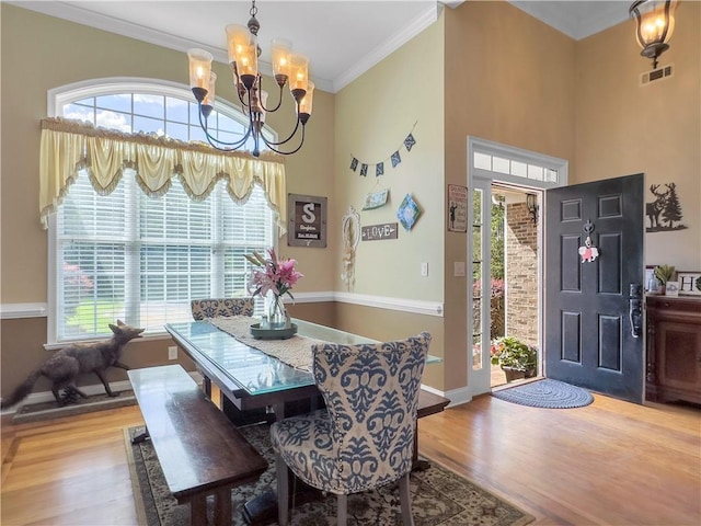 dining area with hardwood / wood-style flooring, crown molding, and a notable chandelier