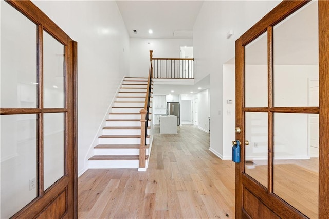 entrance foyer featuring a towering ceiling and light wood-type flooring