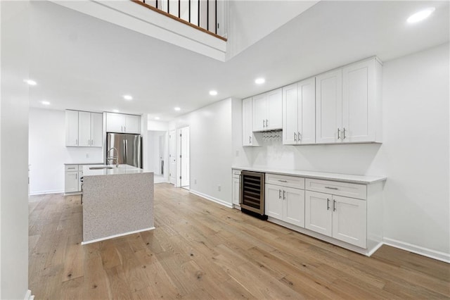 kitchen featuring wine cooler, white cabinetry, stainless steel fridge, and light hardwood / wood-style flooring