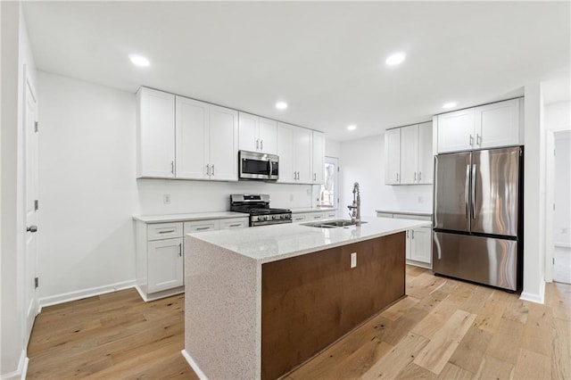 kitchen featuring stainless steel appliances, sink, a center island with sink, and white cabinets