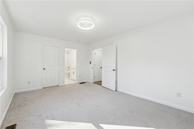 unfurnished bedroom featuring ensuite bath and light carpet