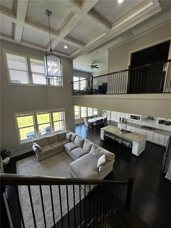 2657 Gray Mill Way, Loganville, GA 30052 - living area with dark wood-type flooring, a high ceiling, coffered ceiling, a chandelier, and beam ceiling