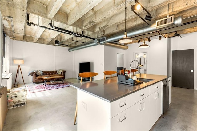 kitchen with concrete floors, white cabinetry, a kitchen island with sink, visible vents, and a sink
