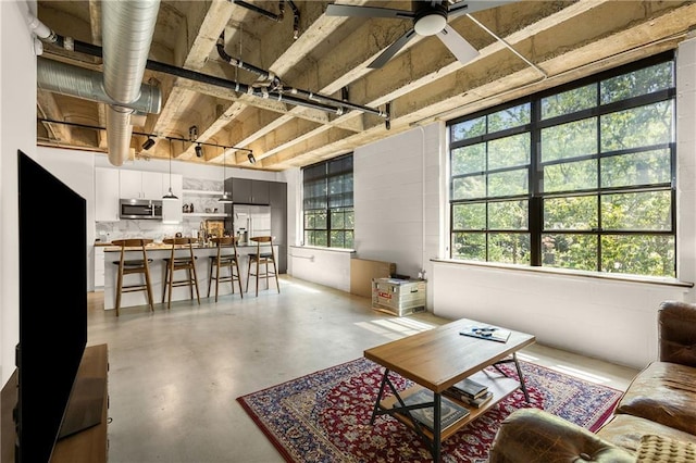 living area with finished concrete flooring and a ceiling fan