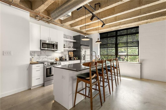 kitchen with dark countertops, open shelves, finished concrete floors, and stainless steel appliances