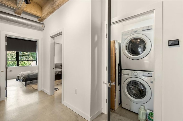 laundry area with baseboards and stacked washing maching and dryer