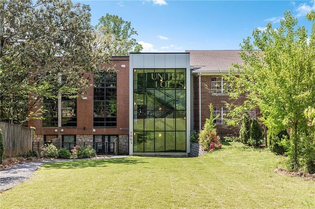 rear view of property with a yard, fence, and brick siding