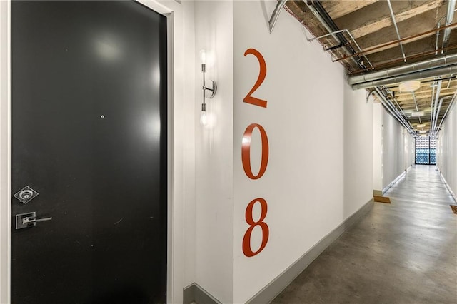 corridor with baseboards and finished concrete floors