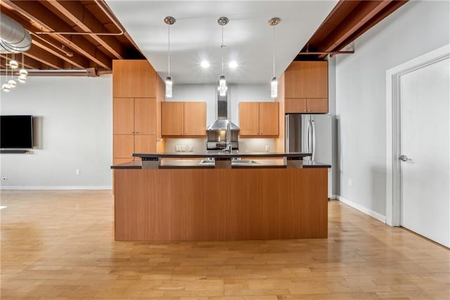 kitchen with stainless steel refrigerator, light hardwood / wood-style flooring, wall chimney exhaust hood, and pendant lighting