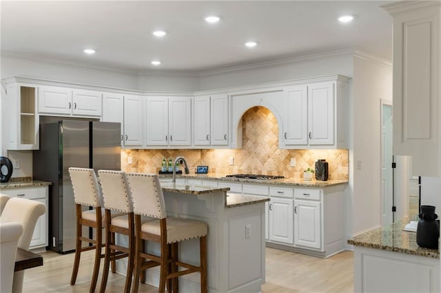 790 Thornberry Dr, Alpharetta, GA 30022 - kitchen featuring stainless steel appliances, light wood finished floors, tasteful backsplash, a breakfast bar area, and light stone countertops