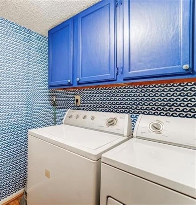 laundry room with cabinets, washing machine and clothes dryer, and a textured ceiling