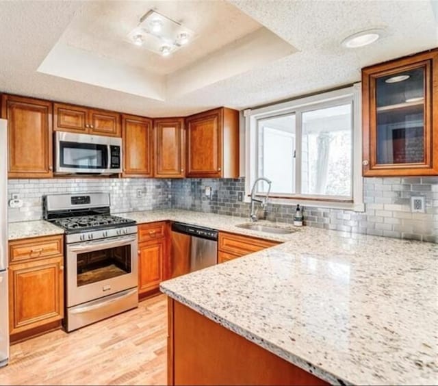 kitchen featuring light stone countertops, a textured ceiling, appliances with stainless steel finishes, and a tray ceiling