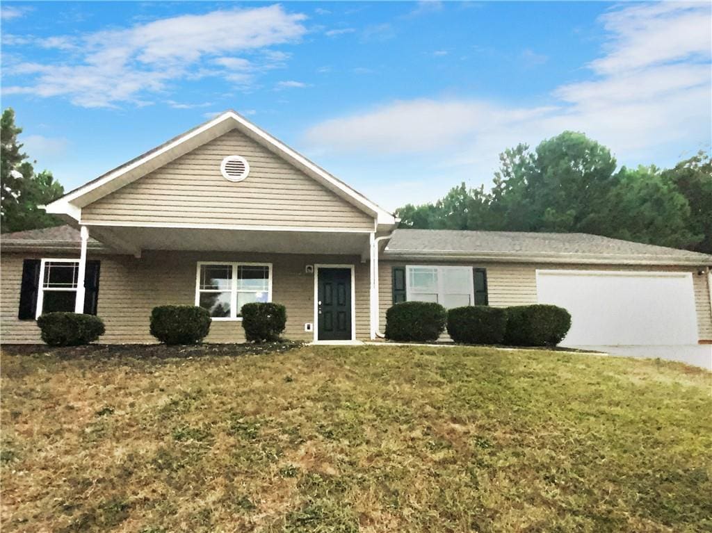 ranch-style house featuring an attached garage, a front lawn, and driveway