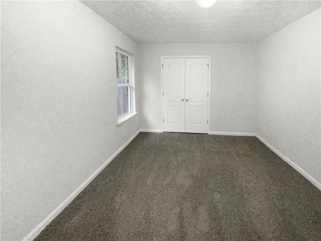 unfurnished bedroom featuring a closet, dark colored carpet, and a textured ceiling