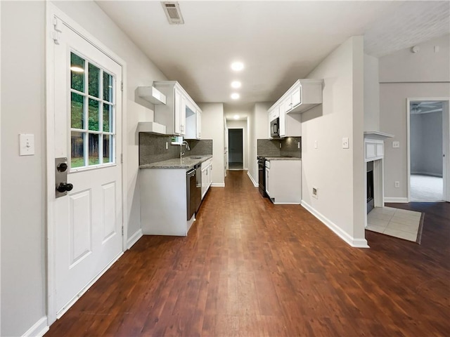 kitchen with white cabinets, backsplash, light stone countertops, and dark hardwood / wood-style floors