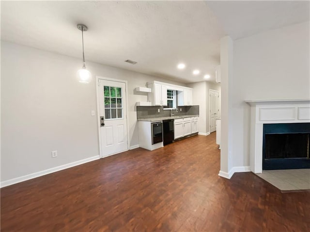 kitchen with hanging light fixtures, white cabinets, black dishwasher, dark hardwood / wood-style floors, and sink