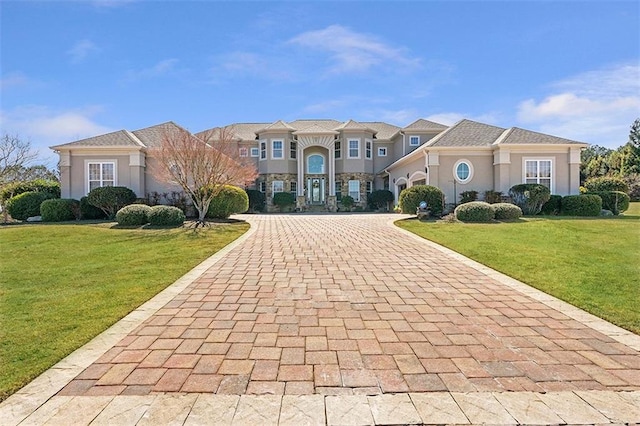 view of front of property with stucco siding, decorative driveway, and a front lawn