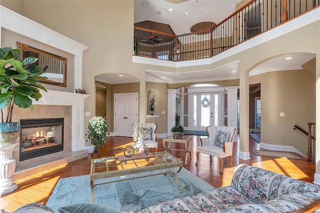 living room with a fireplace, decorative columns, wood finished floors, and baseboards