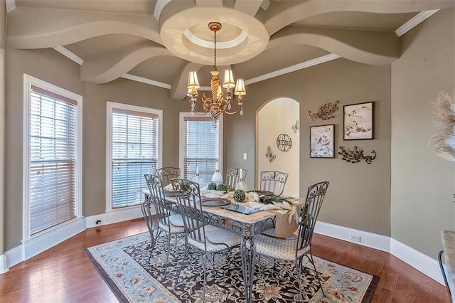 dining room featuring wood finished floors, baseboards, an inviting chandelier, arched walkways, and crown molding