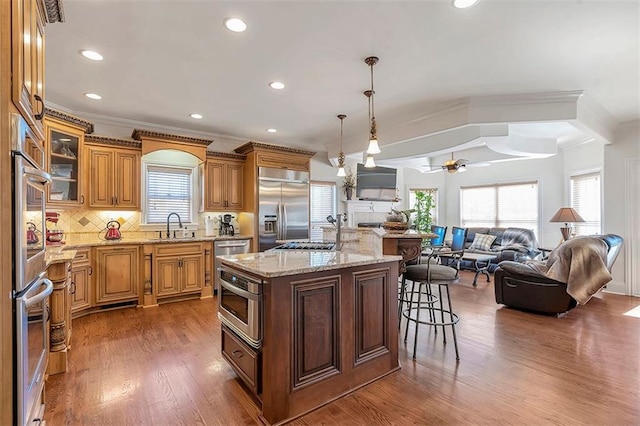 kitchen featuring tasteful backsplash, open floor plan, a breakfast bar area, appliances with stainless steel finishes, and a sink