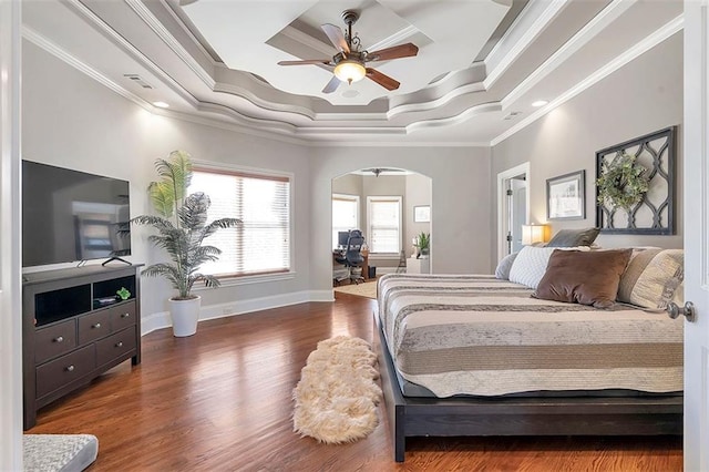 bedroom featuring wood finished floors, visible vents, a tray ceiling, arched walkways, and ornamental molding