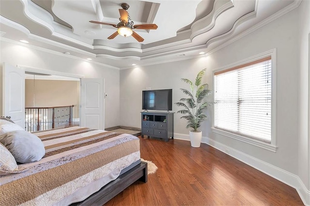 bedroom with a ceiling fan, wood finished floors, baseboards, a tray ceiling, and crown molding