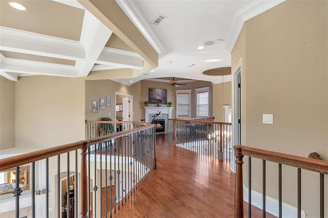 corridor featuring wood finished floors, visible vents, coffered ceiling, crown molding, and beamed ceiling