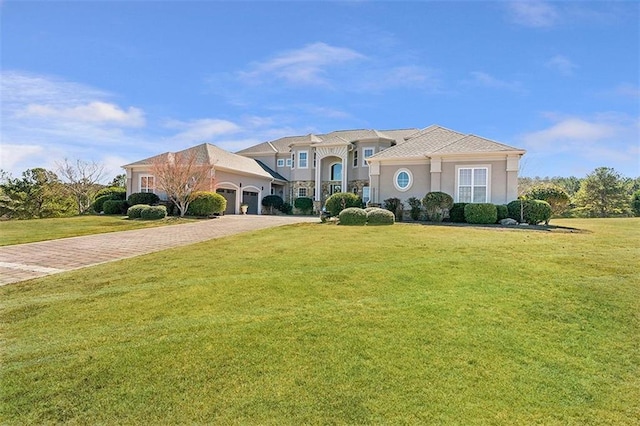 mediterranean / spanish home featuring a front yard, decorative driveway, a garage, and stucco siding