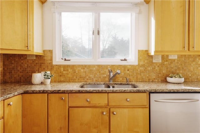 kitchen featuring light stone countertops, dishwasher, sink, and decorative backsplash