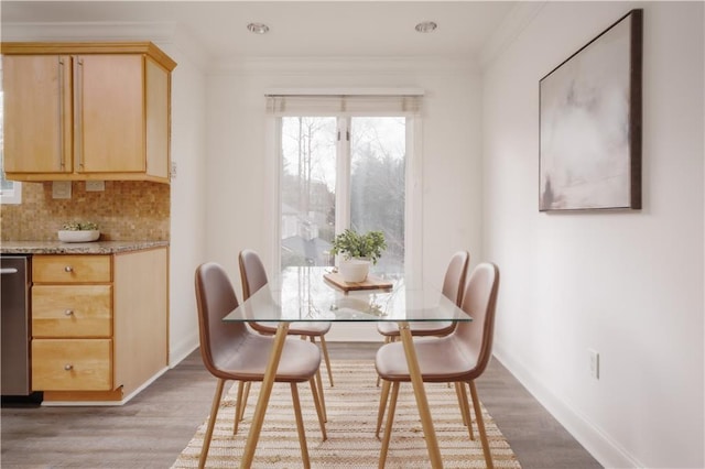 dining space with ornamental molding and light hardwood / wood-style flooring