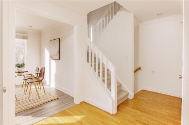 stairs featuring hardwood / wood-style floors and crown molding