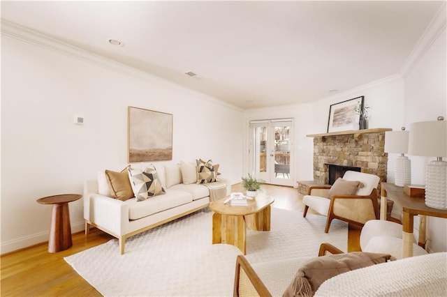 living room featuring a stone fireplace, ornamental molding, and light hardwood / wood-style floors