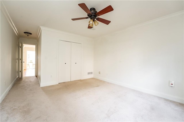 unfurnished bedroom with light carpet, ornamental molding, a closet, and ceiling fan