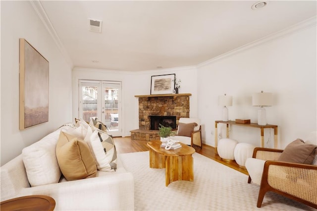 living room with crown molding, a fireplace, and light hardwood / wood-style floors