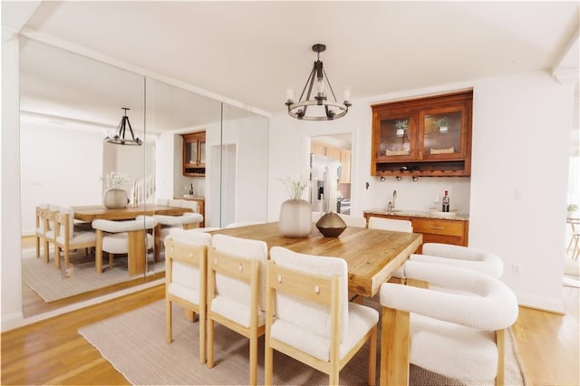 dining area with wood-type flooring, sink, and a chandelier