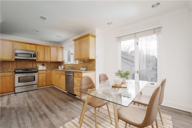 kitchen featuring crown molding, appliances with stainless steel finishes, decorative backsplash, and light hardwood / wood-style flooring