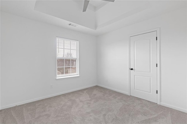 carpeted empty room featuring ceiling fan and a tray ceiling