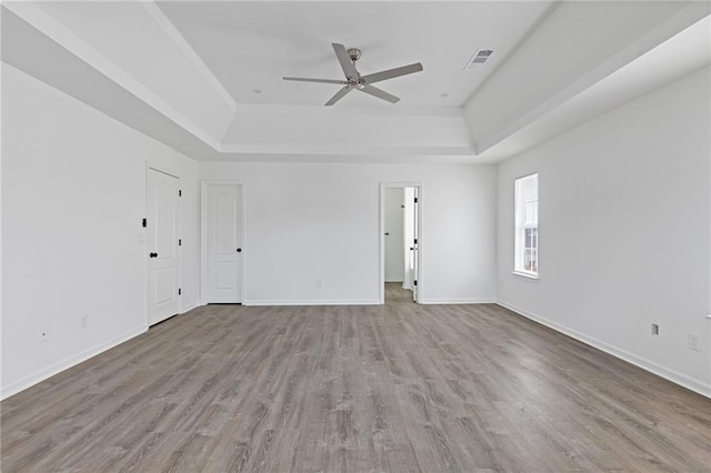 spare room with ceiling fan, light wood-type flooring, and a tray ceiling