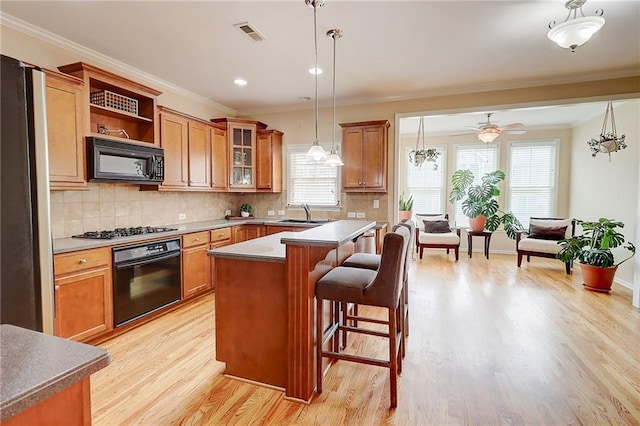 1160 Newpark View Pl Unit 8, Mableton, GA 30126 - kitchen with black appliances, plenty of natural light, brown cabinetry, a breakfast bar area, and crown molding