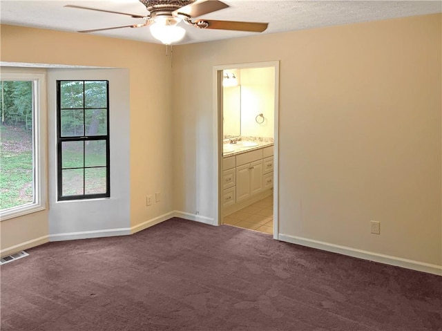 unfurnished bedroom featuring sink, connected bathroom, light tile patterned floors, and ceiling fan