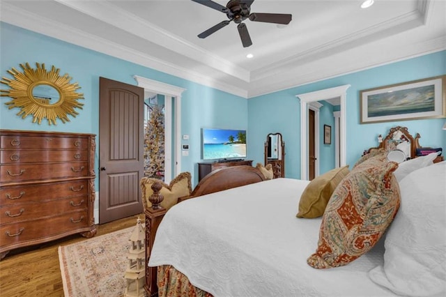 bedroom with recessed lighting, a tray ceiling, wood finished floors, and ornamental molding