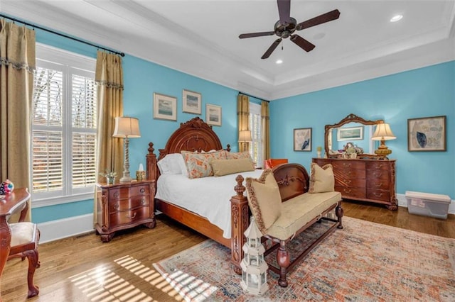 bedroom featuring baseboards, a tray ceiling, and wood finished floors