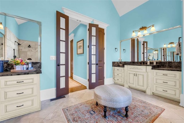 bathroom with vanity, tiled shower, vaulted ceiling, french doors, and tile patterned floors